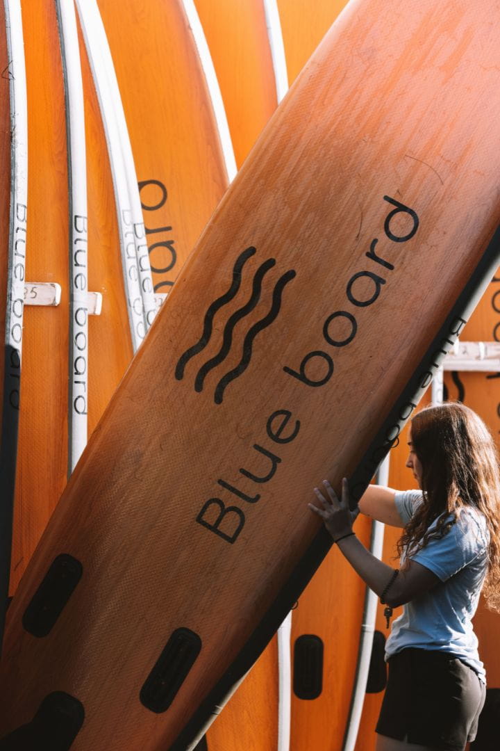 Employée Canots Légaré déplaçant une planche à pagaie au soleil