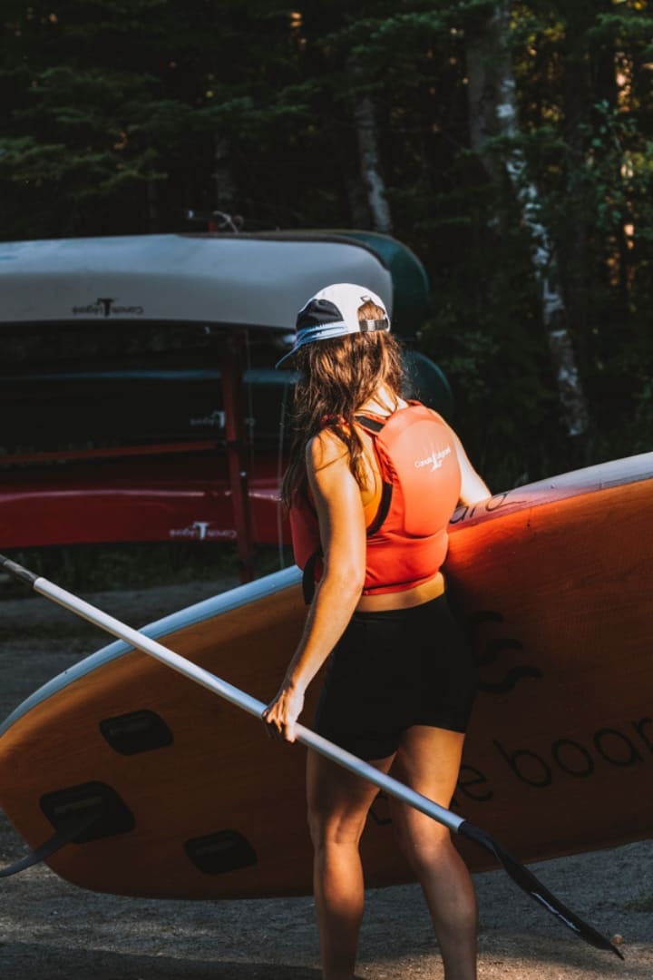Transport d'une planche à pagaie sur la plage chez Canots Légaré