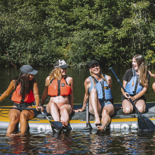 Groupe d'amies en planche à pagaie familiale l'été