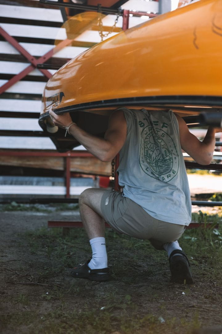 Employé Canots Légaré transportant un canot sur ses épaules